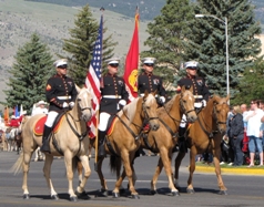 Riders on horseback carrying flags in the Cody Parade