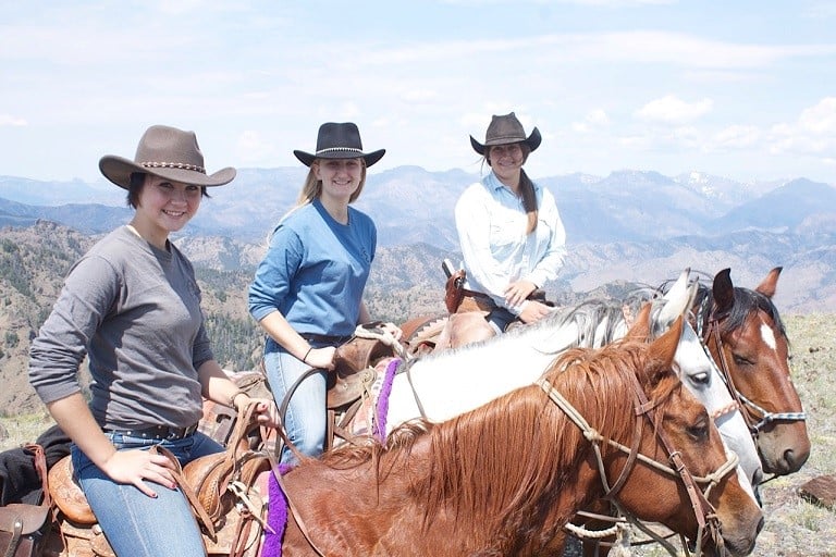 Three women on horseback with mountains in the background