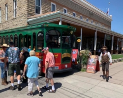 Elderly visitors are walking next to the Cody Trolley Tour bus at Sheridan Avenue.