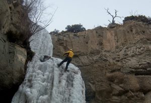 An ice climber scales the side of a cliff