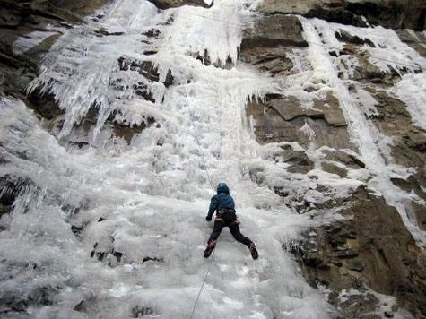 An ice climber climbs the side of a cliff