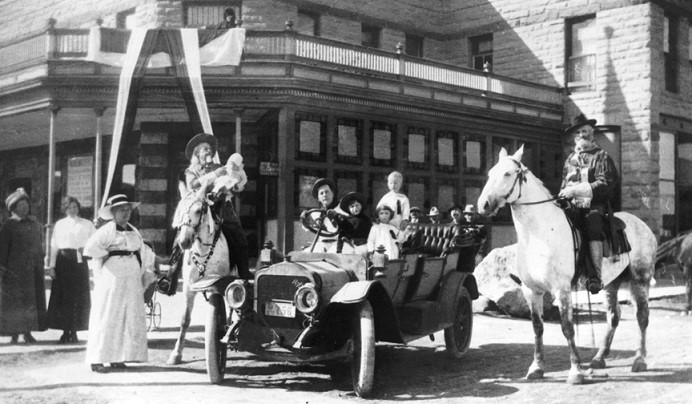 An archive photo of people in a car and on horseback in Cody, Wyoming