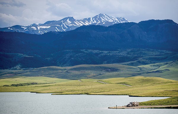 A tranquil body of water with a charming wooden house nearby, nestled in a beautiful natural setting.