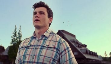 A young man staring off into the distance, wearing a plaid shirt
