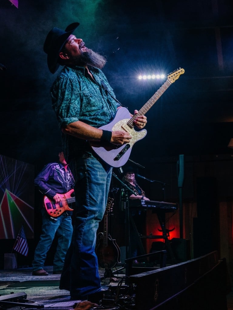 A man playing guitar and singing on stage in a club