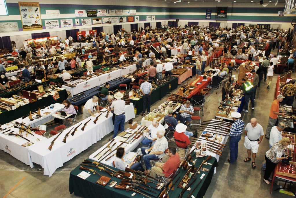A bunch of people walking around a gun expo in a building
