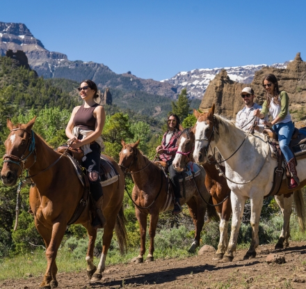 A group travels by horseback with a guide in Cody Yellowstone