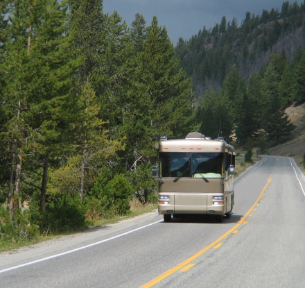 A large Class A motorohome traveling down the road in Yellowstone National Park.